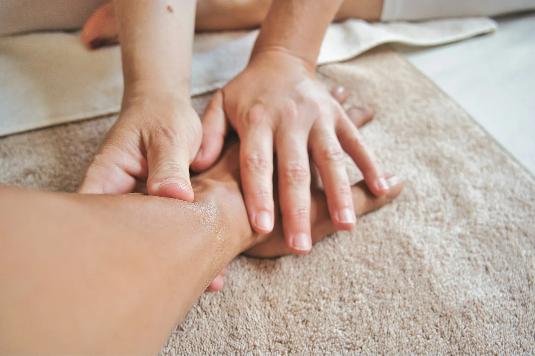 A therapist massaging a hand and forearm resting on a towel