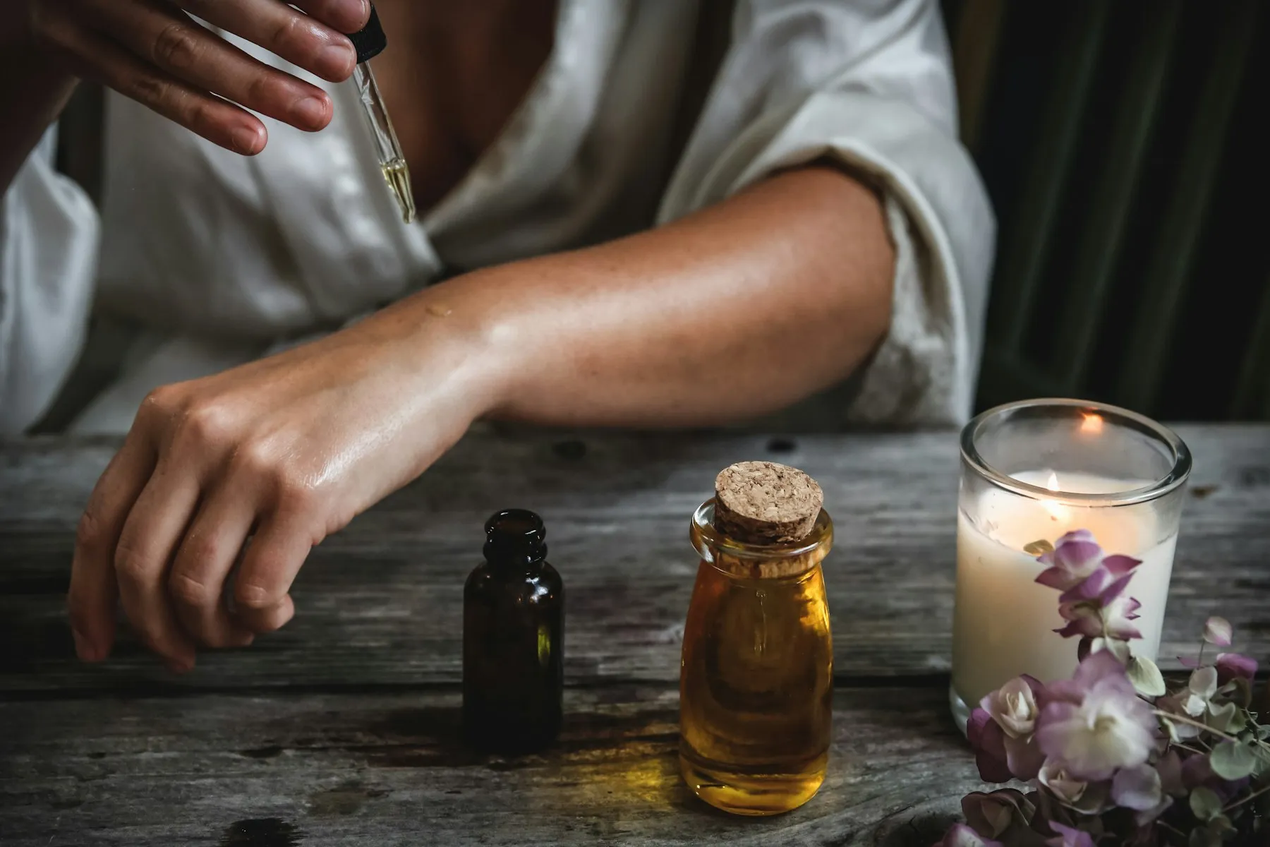 Herbal oil being applied to the forearm from a glass dropper