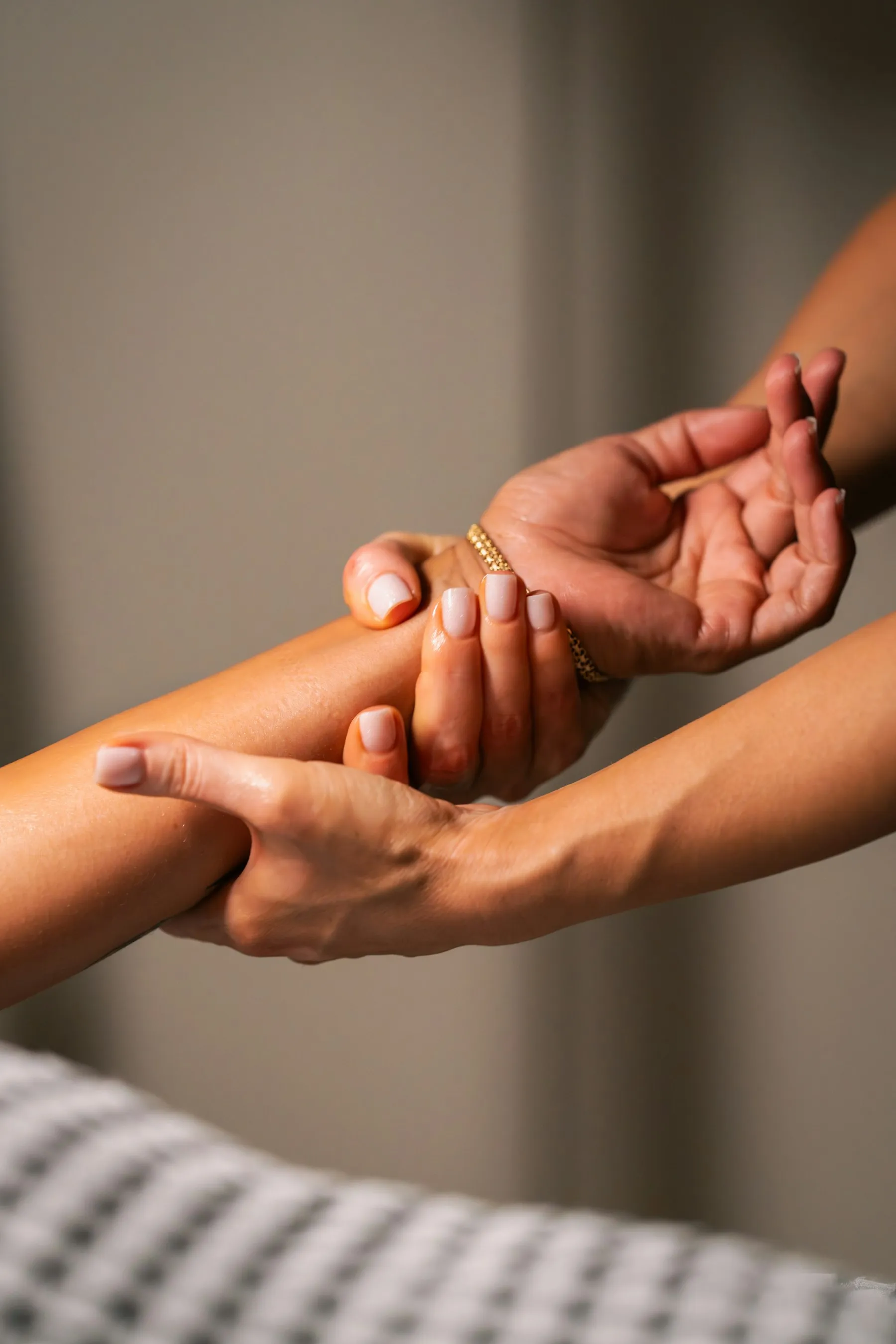 A therapist working warm oil along a forearm with both hands