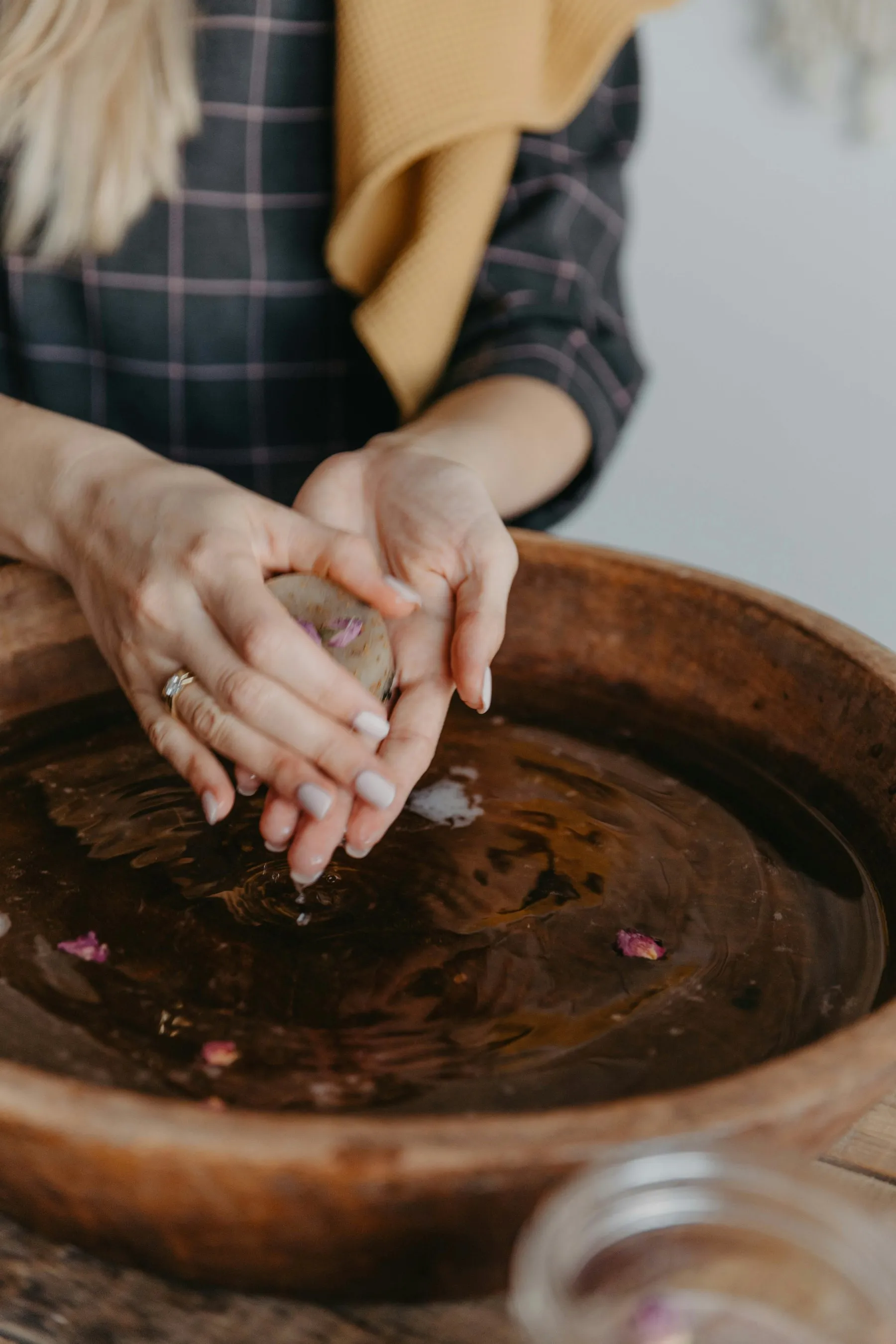 Hands cupped over a copper bowl of warm herbal water